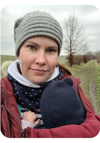 Karolin unterwegs mit ihrem Baby in der Trage bei einem Spaziergang in der Natur — alltagsnaher und bindungsorientierter Familienalltag mit Baby