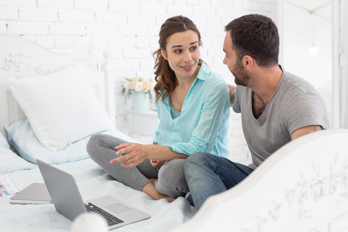Paar sitzt zusammen mit Laptop und informiert sich über Babyvorbereitungskurs in Dresden