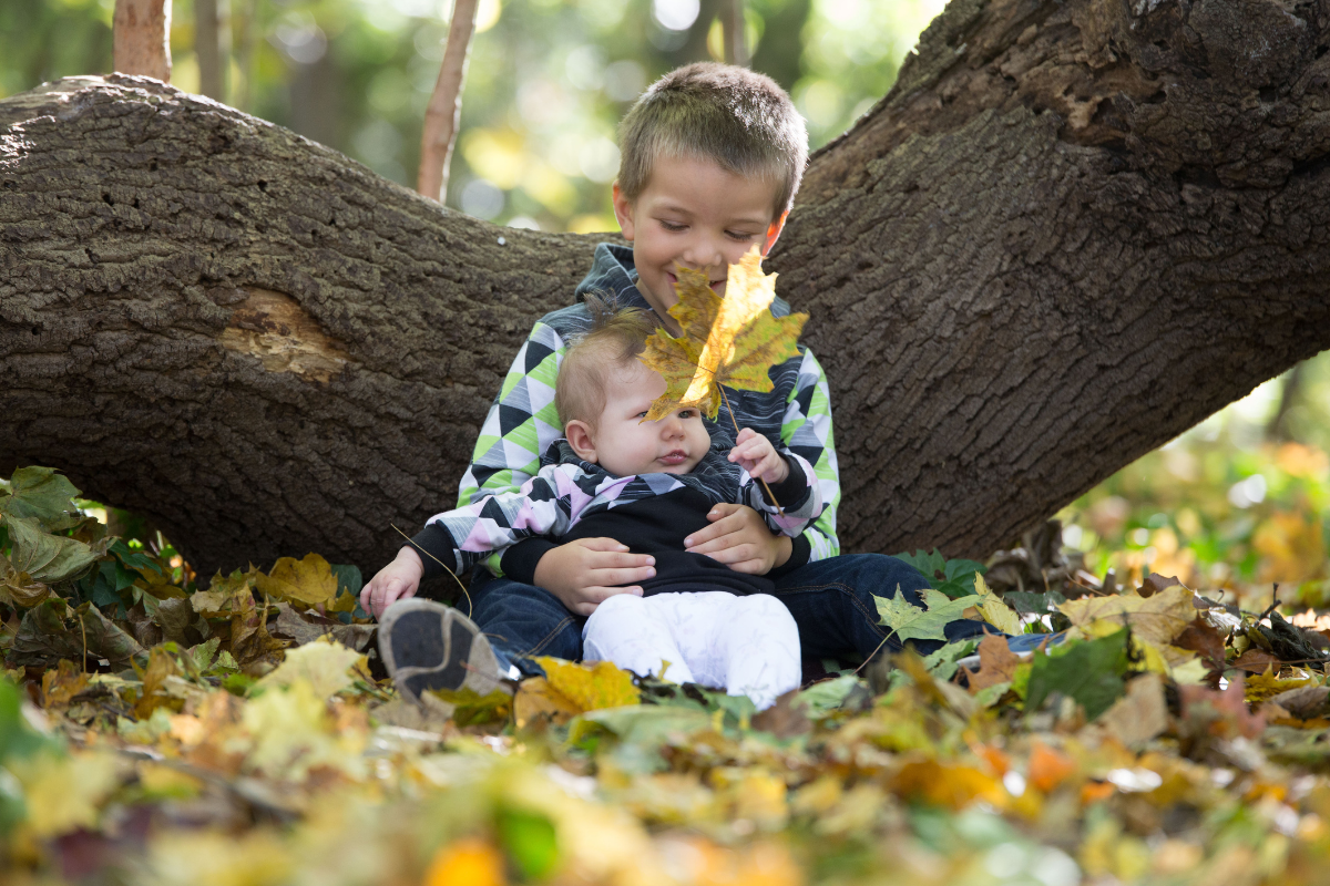 Kind hält Baby auf dem Schoß und erlebt die Beziehung als große Schwester oder großer Bruder in Dresden